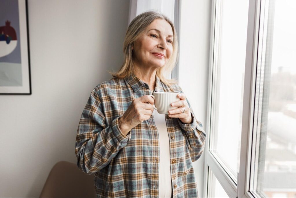 Widow happy and holding a mug in her new condo, thanks to help from Bonner Realty agents.