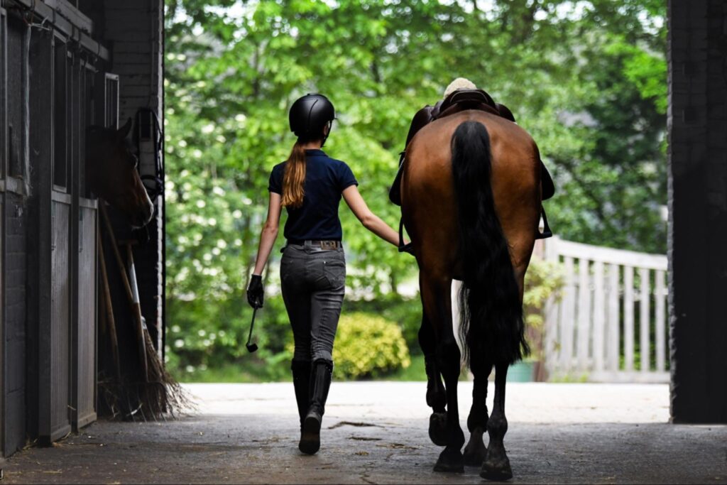 Young female homeowner walking horse out on her new property.