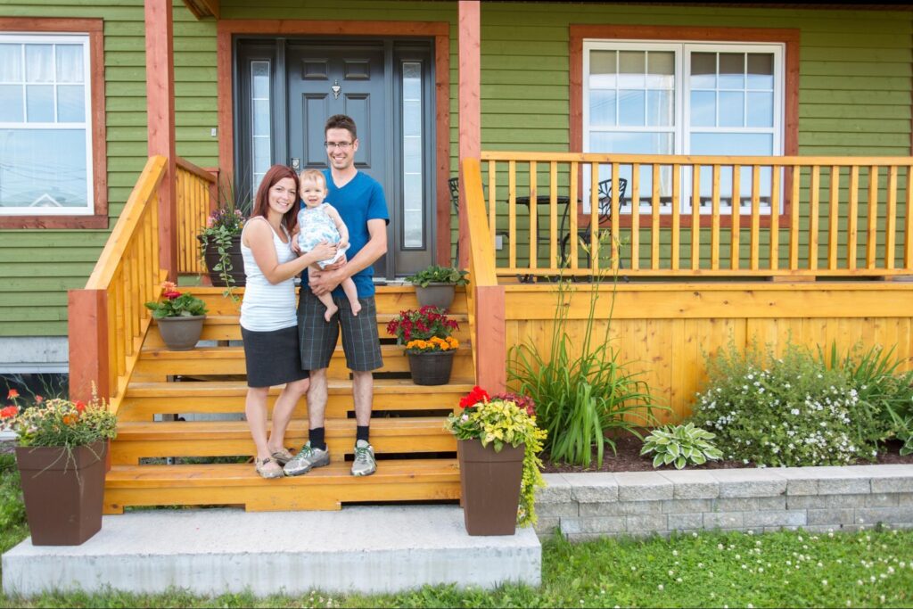 Family standing on the steps of their new home, with a better understanding of real estate vocabulary.