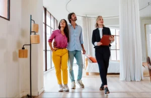 A realtor showing a couple a house represents how a real estate marketing plan can boost your business.